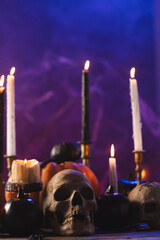 Fototapeta premium Vertical image of pumpkins, skulls and candles with copy space on purple background