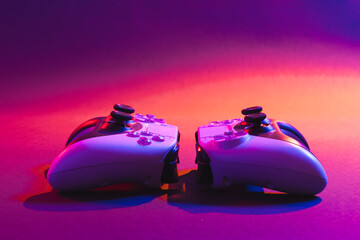Composite of video game pads and copy space on neon background