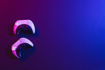 Composite of video game pads and copy space on neon background © vectorfusionart