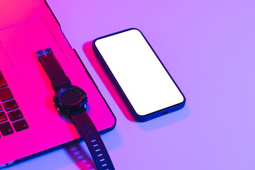 Composite of laptop, smartwatch, smartphone with copy space on neon background