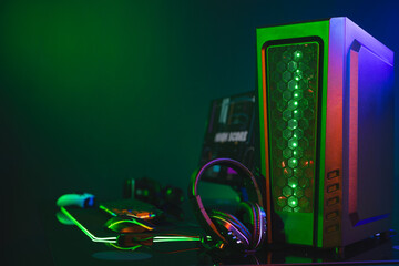 Composite of computer, keyboard with video game accessories with copy space on neon background