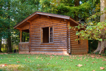 Beautiful wooden house or hut made with wood logs. Wooden hut in the yard overgrown with plants