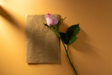 Obraz premium Pink rose flower on brown paper and copy space on orange background