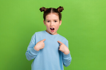 Portrait of confused little girl with brown buns hairstyle wear blue pullover directing at herself...