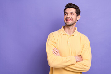 Photo of funky thoughtful man dressed yellow shirt arms folded looking empty space isolated purple...