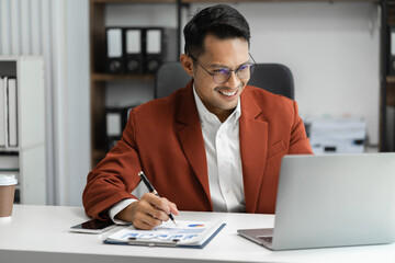 Male writes information businessman working on laptop computer writing business plan while sitting in office.