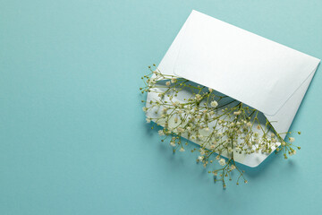 White flowers in white envelope and copy space on blue background