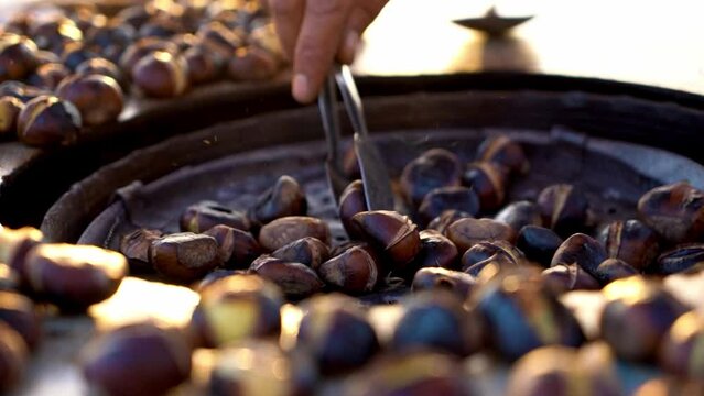 Peddler selling roasted chestnuts on the street, tasty chestnut on a grill