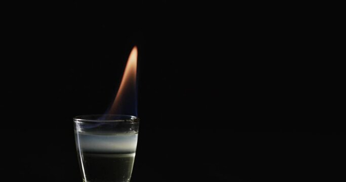 Video of lit alcohol with orange fire flame and copy space on black background