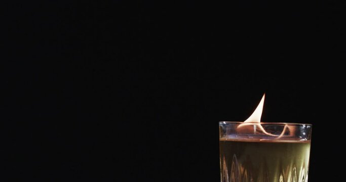 Video of alcohol with yellow fire flames and copy space on black background