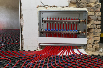 Main control manifold of house heating system, work in progress on construction site for a flat residence building - obrazy, fototapety, plakaty