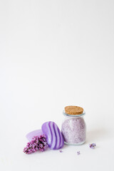 Fototapeta na wymiar Lilac spa. Sea salt, washcloth mitten, lilac flowers, sea salt handmade soap. Natural herbal cosmetics with flowers on a light background. Relaxation concept. Cosmetic procedures. Copy space.