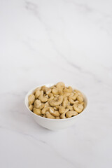Cashew in a white bowl on a marble table
