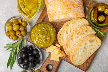 Ciabatta and olives. Fresh italian ciabatta bread with herbs, olive oil,parmesan and pesto sauce, olives on wooden background, top view, copy space.Flatley. Place for text. copy space.