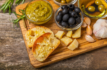 Ciabatta and olives. Fresh italian ciabatta bread with herbs, olive oil,parmesan and pesto sauce, olives on wooden background, top view, copy space.Flatley. Place for text. copy space.