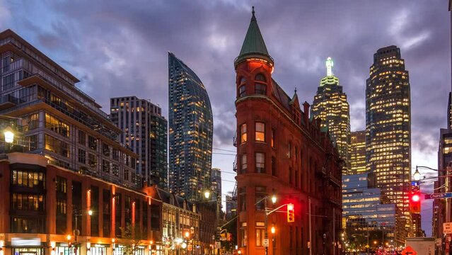 Timelapse view of traffic around historic landmark Flatiron Building at dusk in Downtown Toronto, Ontario, Canada, zoom out. 