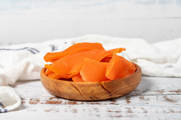 Natural dried mango slices in bowl on wooden background. Fruit snack for a health diet and alternative desert