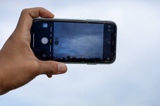 A woman's hand holding a phone taking a picture of the scenery