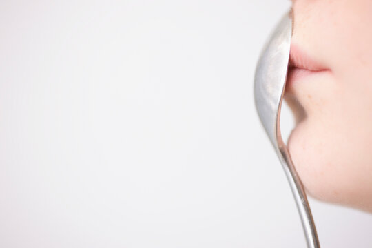 Woman Holding Spoon in front of Mouth
