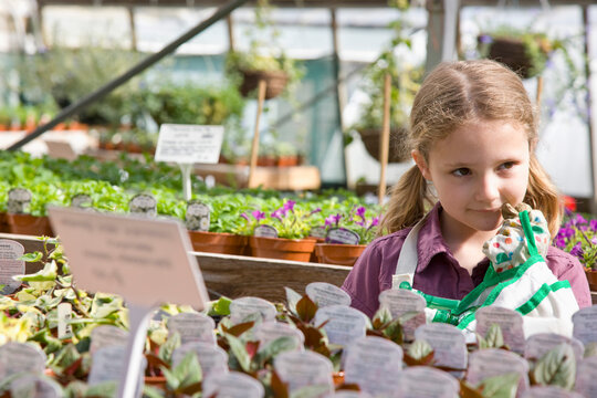 Portrait of young girl amongst flowerpots inside greenhouse
