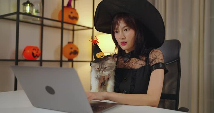 Female influencer wearing mage costume at home. She using laptop in living room at home with her cat.
