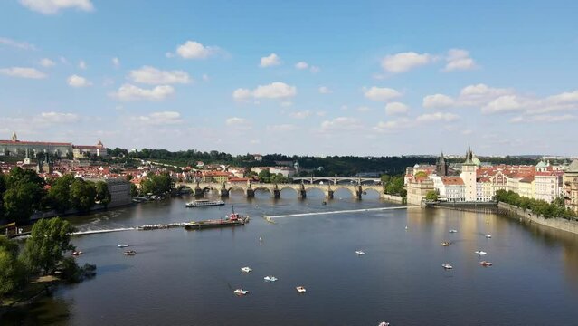 Drone flying over Moldau river facing Charles Bridge in Prague, Czech Republic