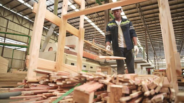 A carpenter works in a wooden factory, Gather wood that has passed through the wood cutter into small pieces. to be sent to be formed into wooden pallets
