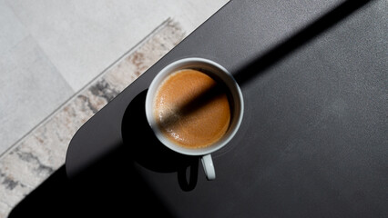 cup of coffee on black table with sunlight