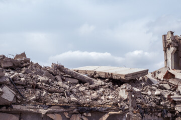 Gray debris of the building in the form of large concrete piles, slabs, beams with remnants of a...