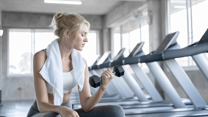 Fototapeta premium Young sport woman exercise with dumbbell at fitness gym. Caucasian girl workout abdominal crunches indoors. Concept of sport, healthcare, physical exercise and beauty shape.