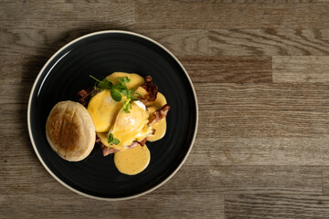 Eggs Benedict with bacon and ham on a wooden table