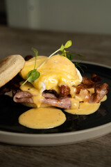 Eggs Benedict with bacon and ham on a wooden table