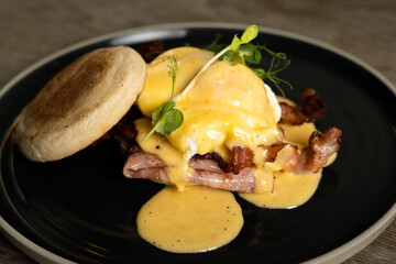 Eggs Benedict with bacon and ham on a wooden table