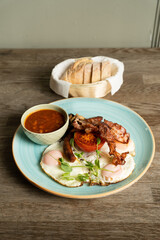 English Breakfast with fried eggs, bacon, Hungarian sausage, mushrooms, baked beans and tomatoes