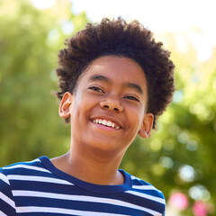 Portrait Of Laughing Young Boy Standing Outdoors In Summer Garden Park Or Countryside