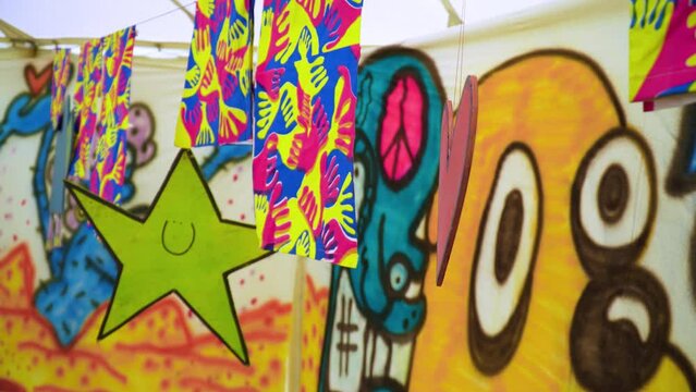cut out symbols of a star and heart made by children in kids are hanged on a string inside a tent that has been painted on