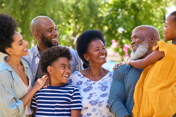 Portrait Of Multi-Generation Family Standing Outdoors In Garden Or Countryside Smiling At Camera