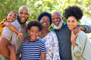 Portrait Of Multi-Generation Family Standing Outdoors In Garden Or Countryside Smiling At Camera