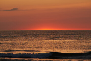 Obraz premium The glowing sun sinking on the horizon of the sea or ocean