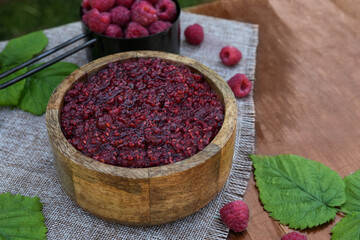 Raspberry jam in the wooden bowl and berries on the dark table. Homemade jam with raspberry. Banner, menu, recipe.  Side view, place for text copy space.