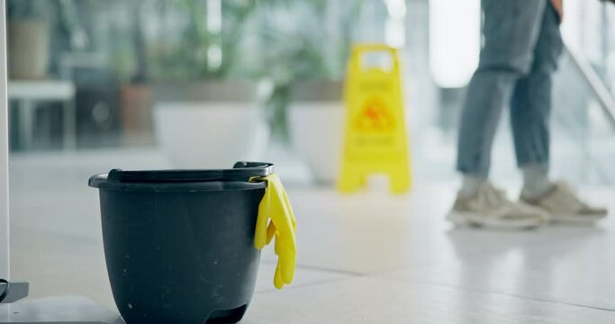 Cleaning, bucket and person with mop in office for cleaner service, professional janitor and maintenance. Manual labor, wet sign and worker for hygiene, disinfection and washing floor in workplace