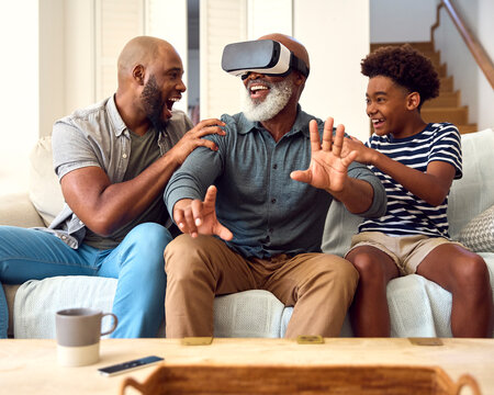 Grandfather Wearing VR Headset As Multi-Generation Male Family Sit On Sofa At Home Together