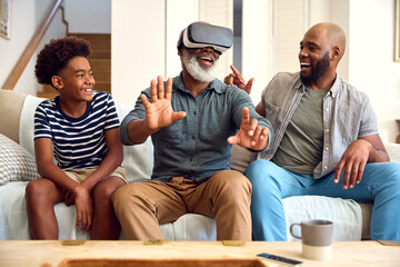 Grandfather Wearing VR Headset As Multi-Generation Male Family Sit On Sofa At Home Together - Powered by Adobe
