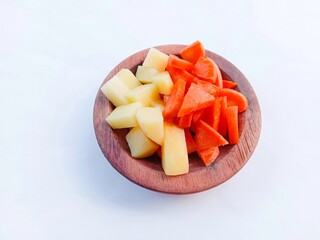 Vegetables salad. Carrot and potato slices in a wooden bowl over a white background. vegetables. cooking preparation. healthy living.
