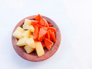 Vegetables salad. Carrot and potato slices in a wooden bowl over a white background. vegetables. cooking preparation. healthy living.
