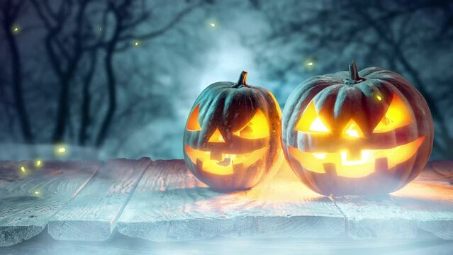 Mysterious candle light flying around carved giant pumpkin with devilish expression over dark forest background with fog. Concept of autumn holiday, Halloween, traditions, mystery, surrealism