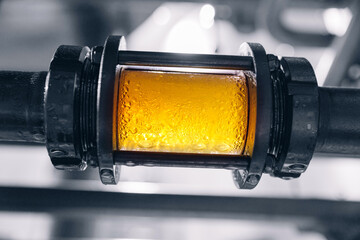 Craft Brewing equipment for quality control, sight glass full of golden beer on stainless steel...