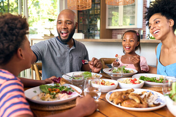 Family Sitting Around Table At Home Enjoying Meal Together