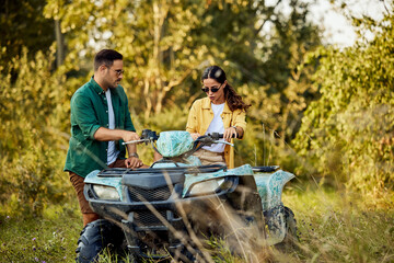 A man and woman fixing a quad bike and continue the adventure in nature. © bnenin