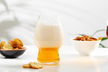 One glass of light amber beer on white table and snacks food